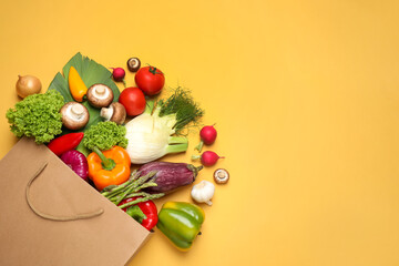 Different fresh vegetables on yellow background, flat lay. Space for text