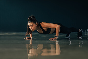 Naklejka na ściany i meble Strong woman doing push ups exercises indoors
