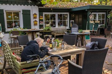 seniorin sitzt in herbstlichem gartenlokal