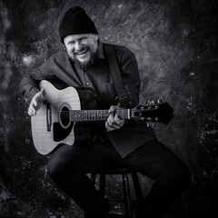 Mature musician plays acoustic guitar emotional studio portrait.