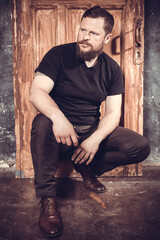 Mature bearded man sitting on vintage door background