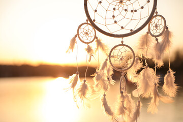 Beautiful handmade dream catcher near river at sunset. Space for text