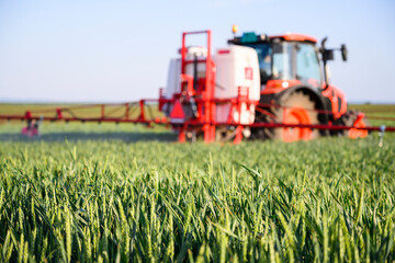 Obraz premium Tractor spraying pesticides wheat field.