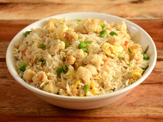 Indian cuisine Healthy and tasty chicken fried rice served in white bowl over a rustic wooden background, selective focus