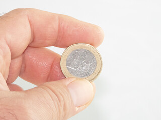 Palma de Mallorca, Spain, November 29, 2020: An adult man's hand holding a 1 euro coin isolated on white background. Illustrative editorial image.