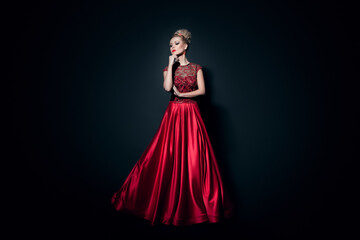 Fulll length image of a beautiful girl dressd in a long fluing red dress, over black background.