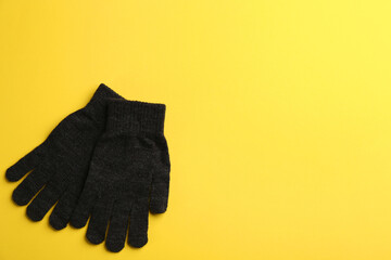 Pair of stylish woolen gloves on yellow background, flat lay. Space for text