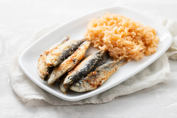 fried small sardines with tomato rice on white dish on ceramic
