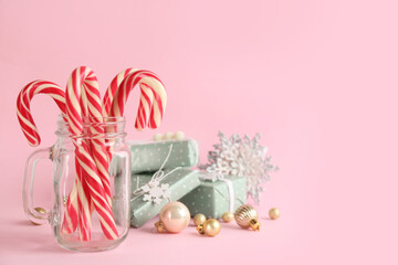 Candy canes, gift boxes and Christmas decor on pink background, space for text