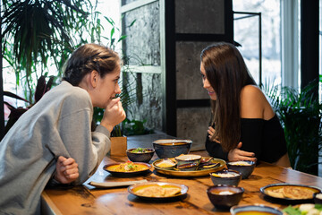 Two highschool girls gossiping in an asian cafe.
