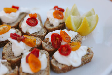 closeup of white platter with red and orange roasted cherry tomatoes on bread with mozzarella