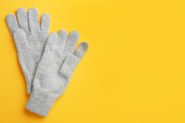 Pair of stylish woolen gloves on yellow background, flat lay. Space for text