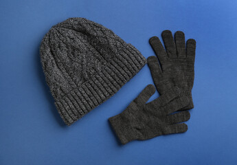 Woolen gloves and hat on blue background, flat lay