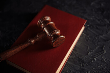 Judge gavel with red book on a table.