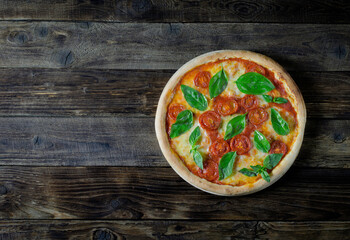 Top view to Italian pizza Margarita with tomato, mozzarella and basil on a wooden board with copy space