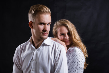 Young beautiful couple studio portrait on black background.