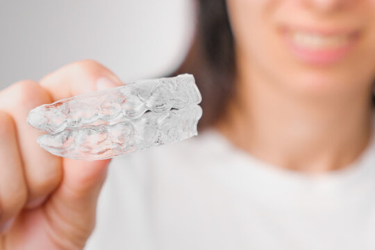 Close up of clear aligners in hand of woman. Orthodontic treatment for whitening and straightening teeth.