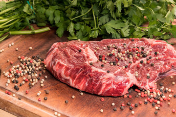 steak of beef on a wooden board with spices and parsley