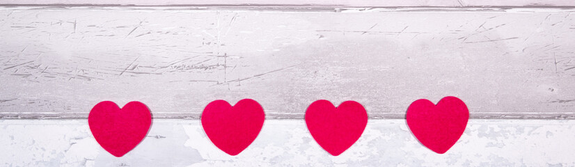 Red felt hearts on a background of old wooden planks resembling an old parquet floor. Concept of valentines day and love in general