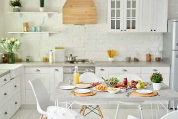 Latin style breakfast on the table. Modern bright white kitchen interior with wooden and white details