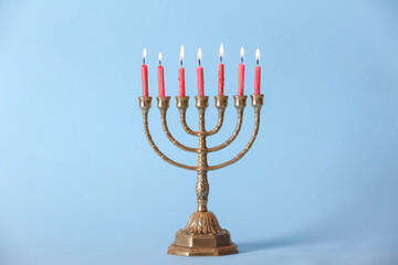 Fototapeta premium Golden menorah with burning candles on light blue background