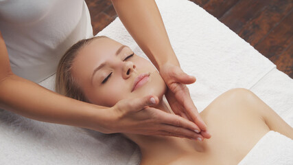 Young, beautiful and healthy woman in massaging salon. Traditional face massage therapy and skin care.