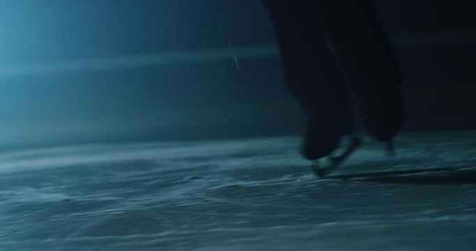 Cinematic close up shot of male figure skater's skating shoes while performing a man's single choreography on ice rink during a competition. Concept of perfection, precision, freedom, passion.