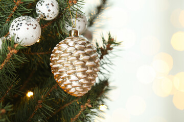 Cone shaped holiday bauble hanging on Christmas tree against blurred lights, closeup. Space for text