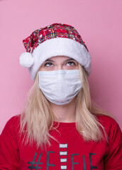 Young woman with medical mask and santa hat on pink  background. Christmas on quarantine. mask safe from coronavirus covid-19 isolated . Happy New Year celebration  merry holiday concept. panorama. 