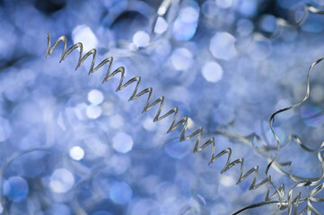 Detail of long spiral twisted aluminum swarf on blue toned background. Closeup of metal waste in...