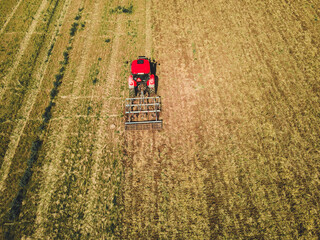 Fototapeta na wymiar Tractor mowing agricultural field. Aerial view. Cultivating field.