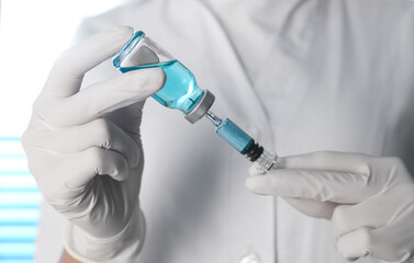 Doctor filling syringe with vaccine from vial, closeup