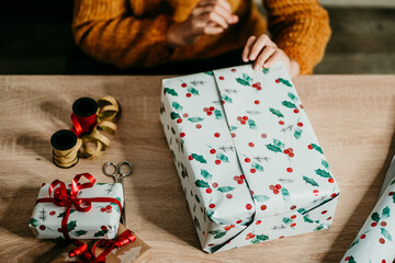 .Pretty young woman in a santa hat wrapping christmas presents at home. Christmas time. Close up