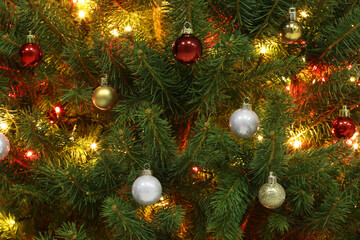 Obraz na płótnie Canvas Glowing bright fairy lights and beautiful baubles on Christmas tree