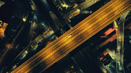Top down of traffic road at night illuminate aerial. Metropolis cityscape with modern buildings at...