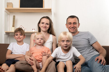 Portrait of big happy family at home. Mom dad and three children look at the camera