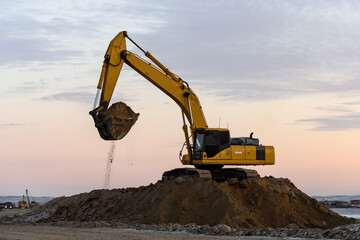 Yellow excavator working on construction site. The road construction.