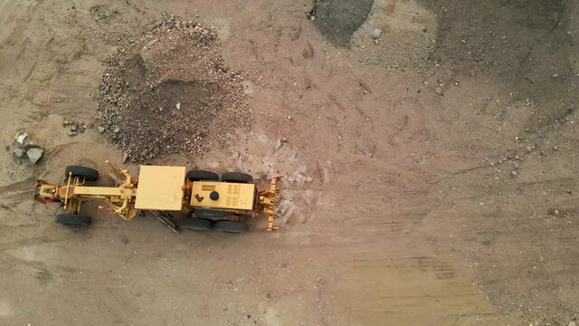 Flyover of a construction grader in a dirt parking lot.