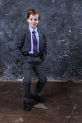 Cute schoolboy dressed in suit studio portrait.