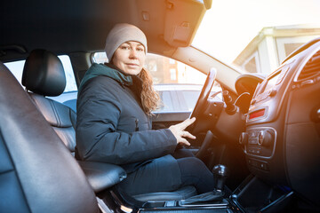 Portrait of young Caucasian smiling woman inside a car, winter clothes