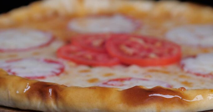 Close-up of delicious appetizing pizza margarita paperoni with red tomatoes and ketchup sauce, baker chef brush the sides of edges of dish with brush, making crisp, fast food and pizzeria concept