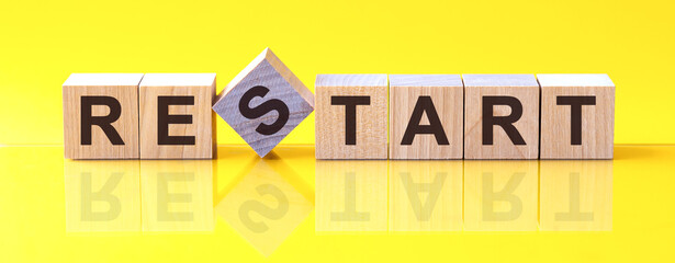 restart word is made of wooden building blocks lying on the yellow table, concept