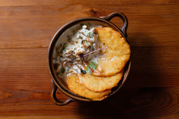 Potato pancakes with mushrooms and bacon in sour cream sauce top view.
