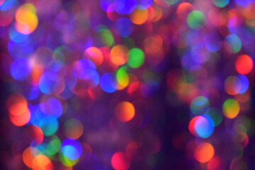 Christmas background, garland in blur. Glowing and festive rainbow light circles created in camera and bokeh lens. Christmas fairy lights are defocused giving a blurry effect.