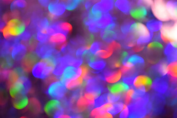 Christmas background, garland in blur. Glowing and festive rainbow light circles created in camera and bokeh lens. Christmas fairy lights are defocused giving a blurry effect.