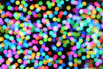 Christmas background, garland in blur. Glowing and festive colored light circles created in camera and bokeh lens. Christmas fairy lights are defocused giving a blurry effect.