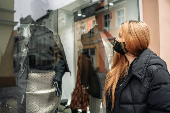 Woman looks at mannequin in shop window. Girl customer near store. Black Friday. Female shopping