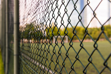 Close-up shot of a metal fence woven on the edge of the sports field in the garden.