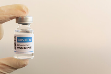 Hand with glove holding Laboratory Vial with Covid-19 coronavirus vaccine. With copy space