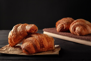 Cup of cappuccino coffee and croissant on dark table